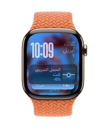 صورة لساعة Apple Watch باللون الذهبي الوردي مع حزام مَجدول بلون مندرين، وتعرض واجهة الساعة التاريخ في أعلى اليسار، والوقت مع الأرقام المكدسة في أعلى اليمين، وأداة الحِمل التدريبي في الأسفل، كل ذلك بتصميم Liquid Glass شبه شفاف