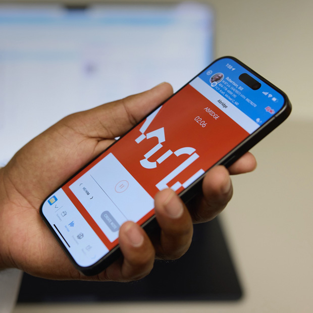 A hand holding an iPhone displaying the Abridge app, which translates patient-clinician conversations into clinical notes.