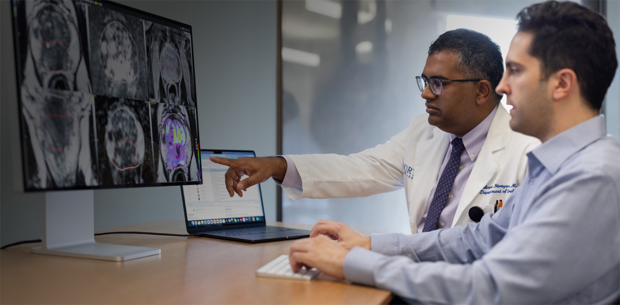 Two doctors looking at radiology images on an iMac.