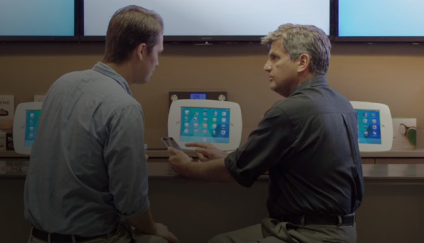 رجلان يجلسان أمام O Bar وينظران إلى شاشة iPhone.